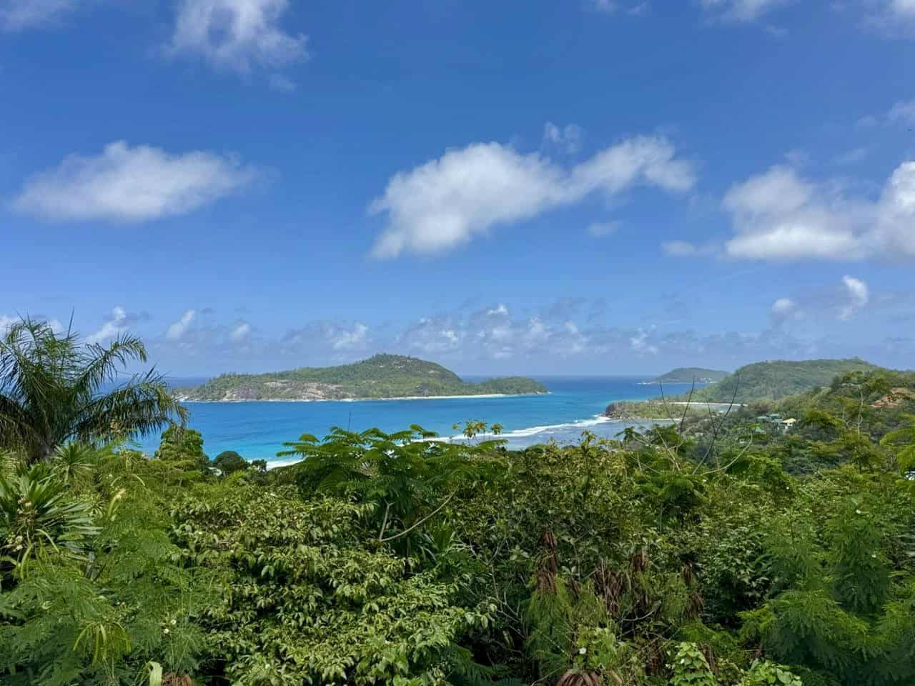 Turquoise beach under blue sky in Seychelles with lush greenery and islets — tropical scenery.