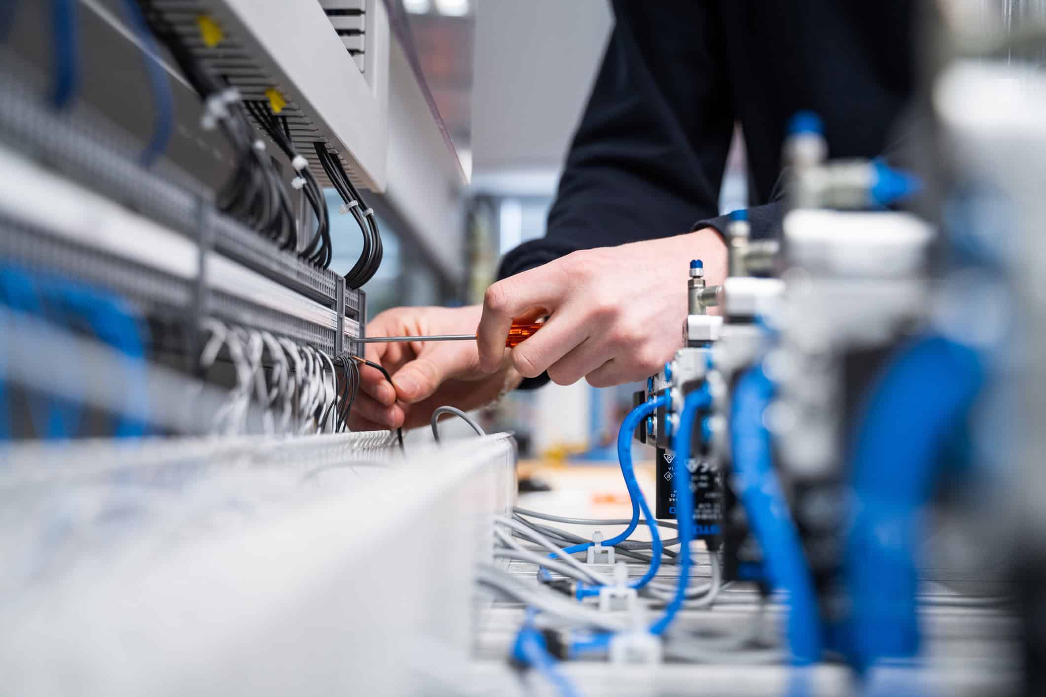 Håndverker som jobber med elektriske kabler og sikringsskap i elektrisk installasjon.