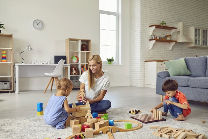 Leketid med foreldre og barn i stue, barnevennlig hjem, lek og moro, trygg familieomsorg, moderne interiør.