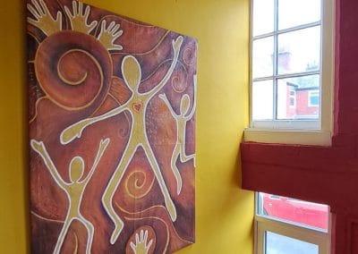 Abstract painting with figures on yellow wall.