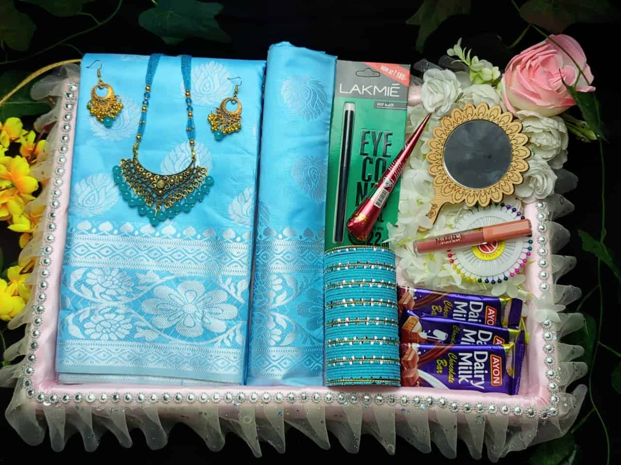 Elegant sky blue katan saree with jewelry and beauty products in gift box.