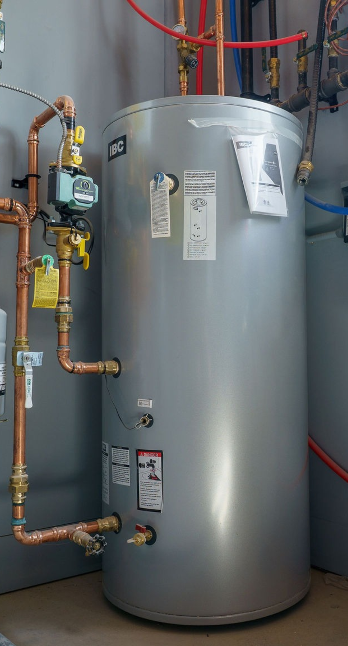 Commercial water heater with plumbing connections in a building.