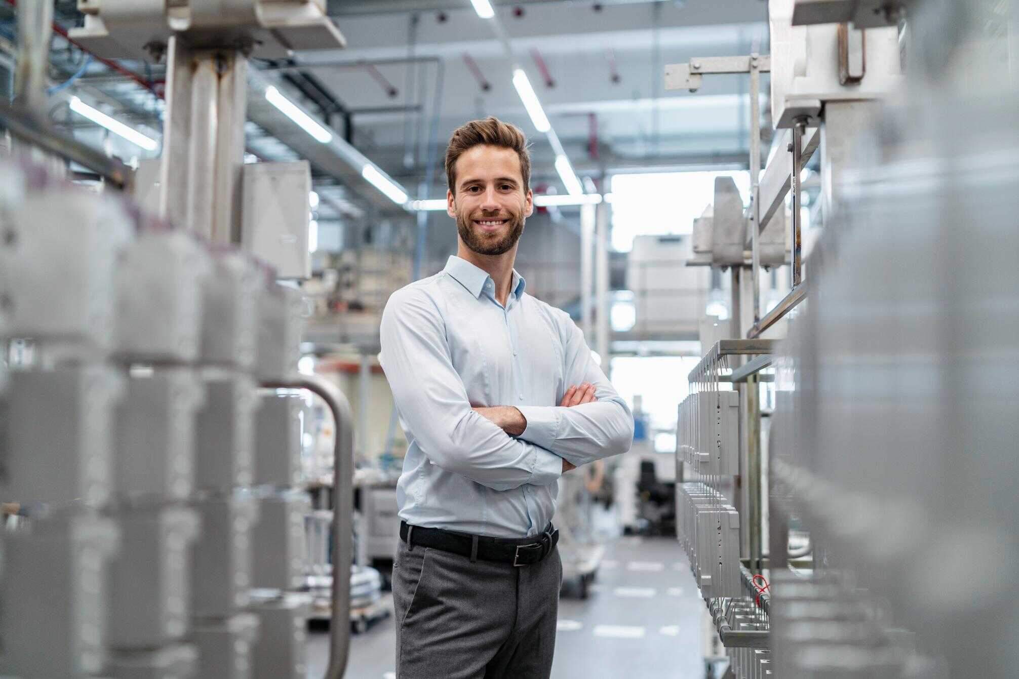 Ingeniero sonriendo en planta industrial, sostenibilidad y economía circular, innovación en proyectos industriales.