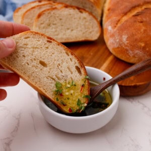 Sliced French bread being dipped in a garlic herb olive oil