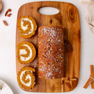 Pumpkin roll with pecans on cutting board.