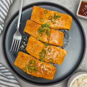 Teriyaki Salmon plated on black plate.