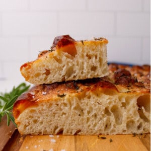 Golden brown homemade no knead focaccia bread topped with fresh rosemary leaves, fresh oregano, and flaky salt.