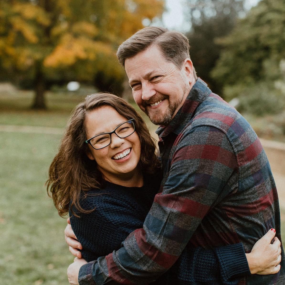 Joyful couple embracing outdoors in autumn, promoting community and spirituality at Singing Feather Ministries.