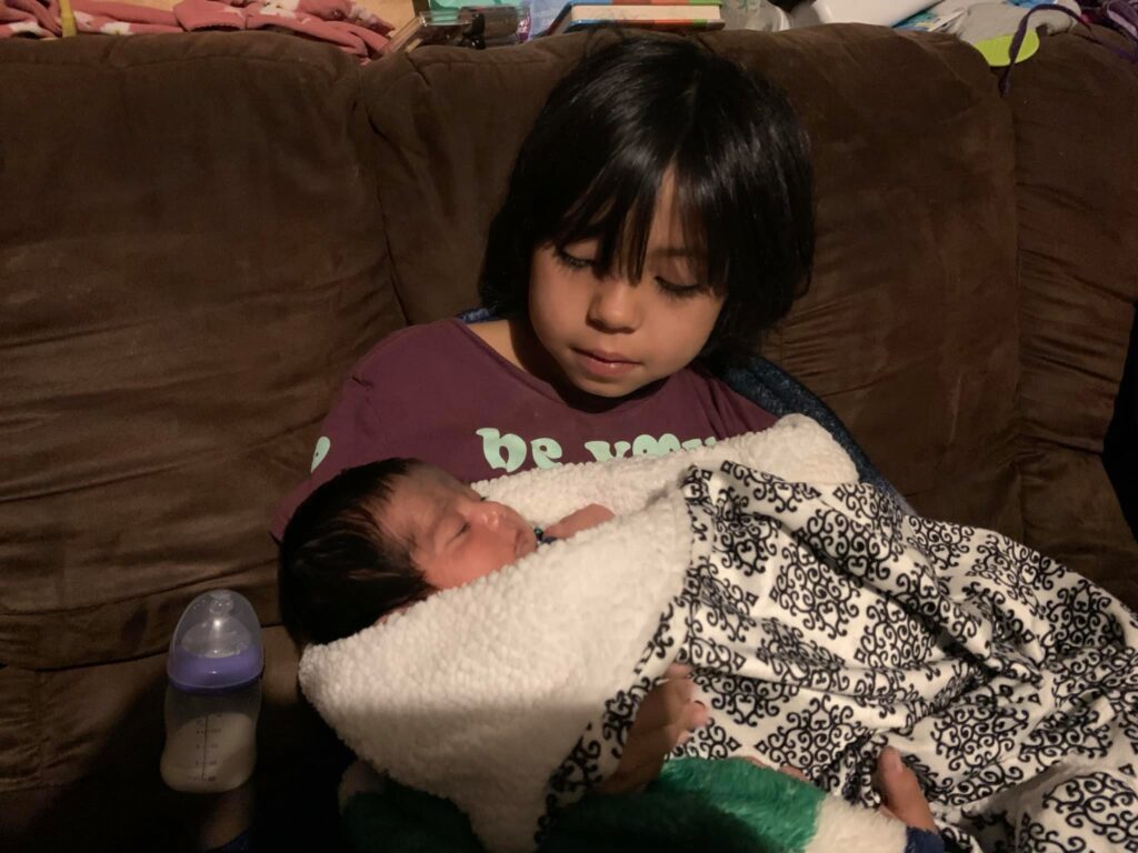 Newborn baby being held by young girl, caring and nurturing, family love.