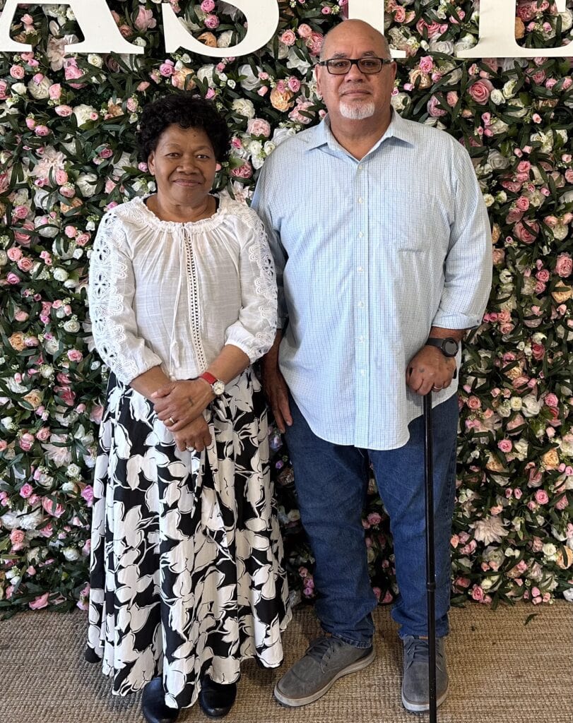 Inspirational couple at Singing Feather Ministries with floral background.
