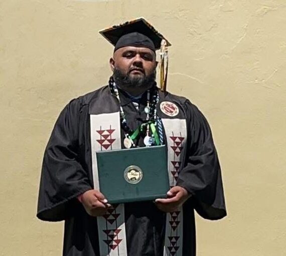 Graduate in cap and gown holding a diploma, celebrating academic achievement.