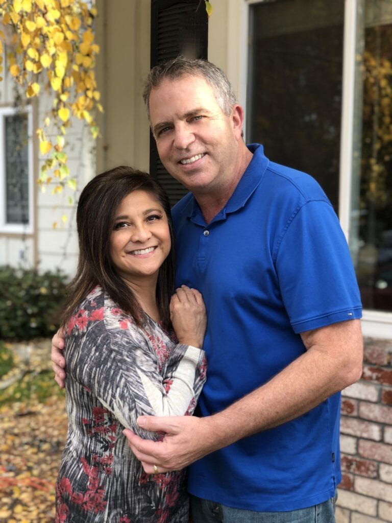 Husband and wife standing outdoors, smiling, representing faith-based community and family in Singing Feather Ministries.