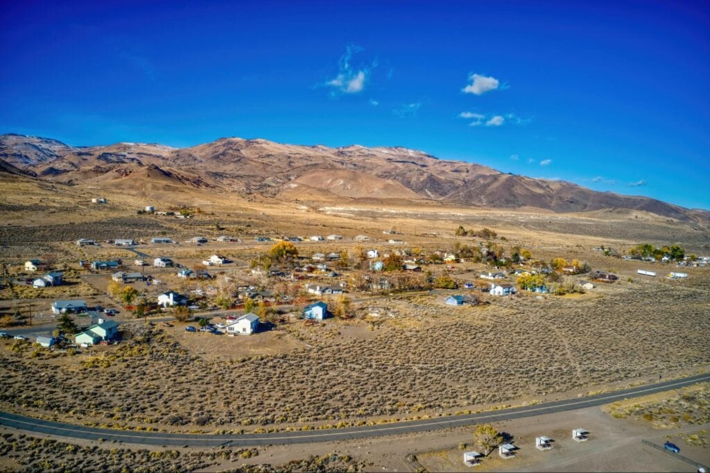 Aerial view of a rural mountain community with scattered homes and desert landscape.