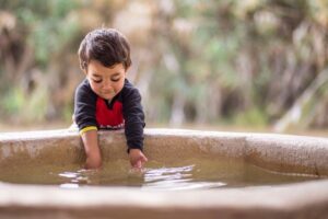 Child pouring water into a sacred basin, symbolizing faith and spiritual growth in Christian ministry.