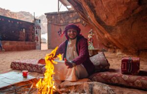 Vibrant fire dance performance in desert campsite with man smiling and traditional garments.