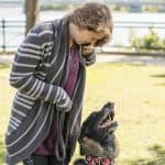 Une femme et un chien de berger allemand jouent dans un parc en plein air, sous un ciel ensoleillé.