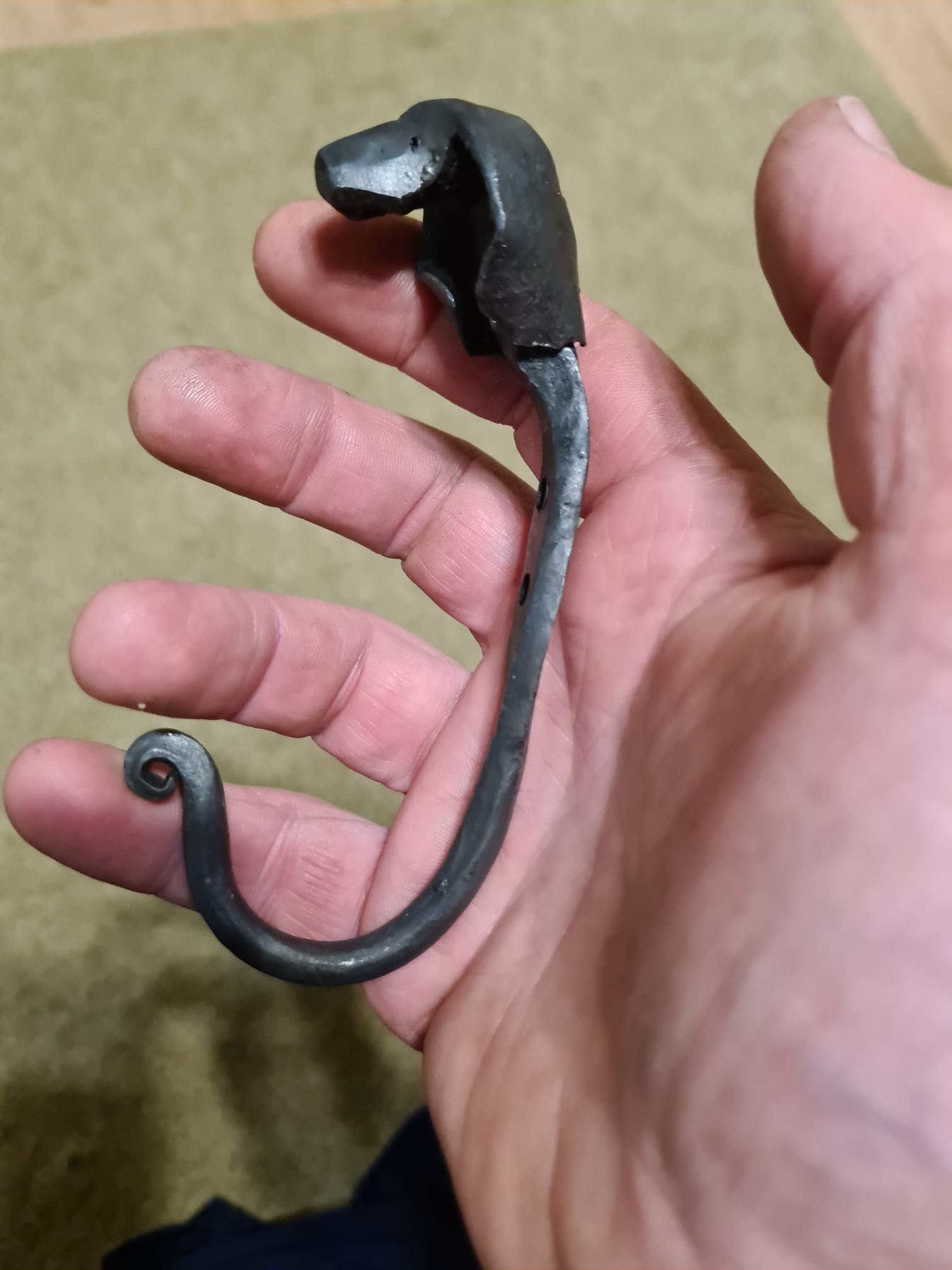Hand holding a metal hook with animal head.
