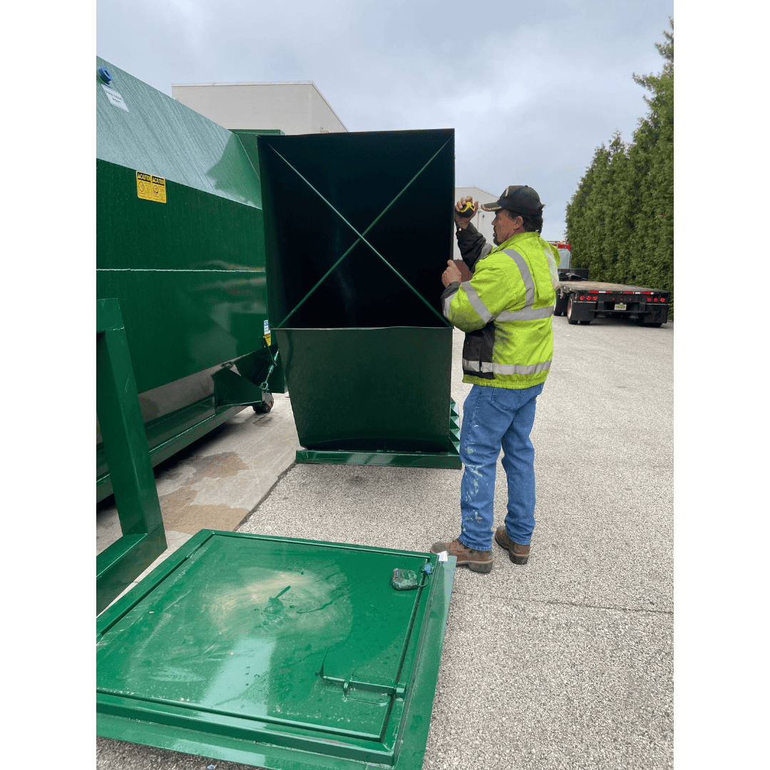 Portable waste container being set up outdoors.