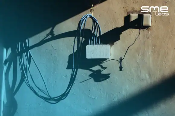 Network cables connected to a wall-mounted device with shadows on the wall.