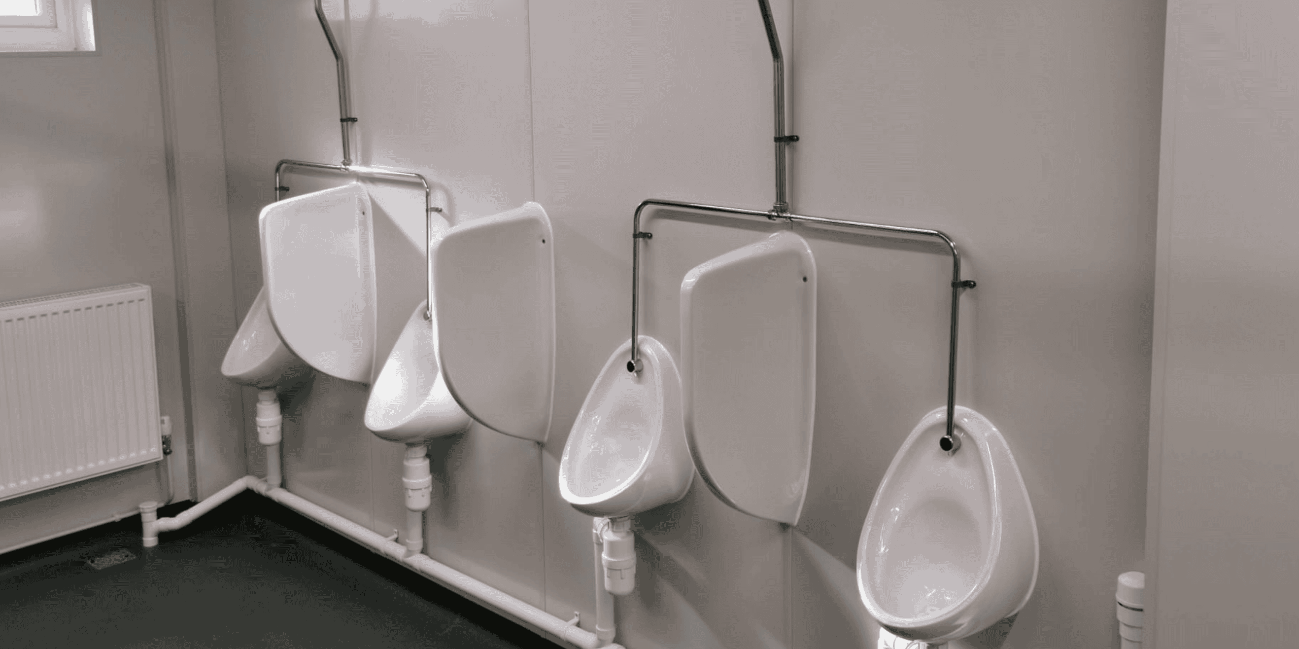 Row of wall-mounted urinals in a clean washroom at MC Trucks site