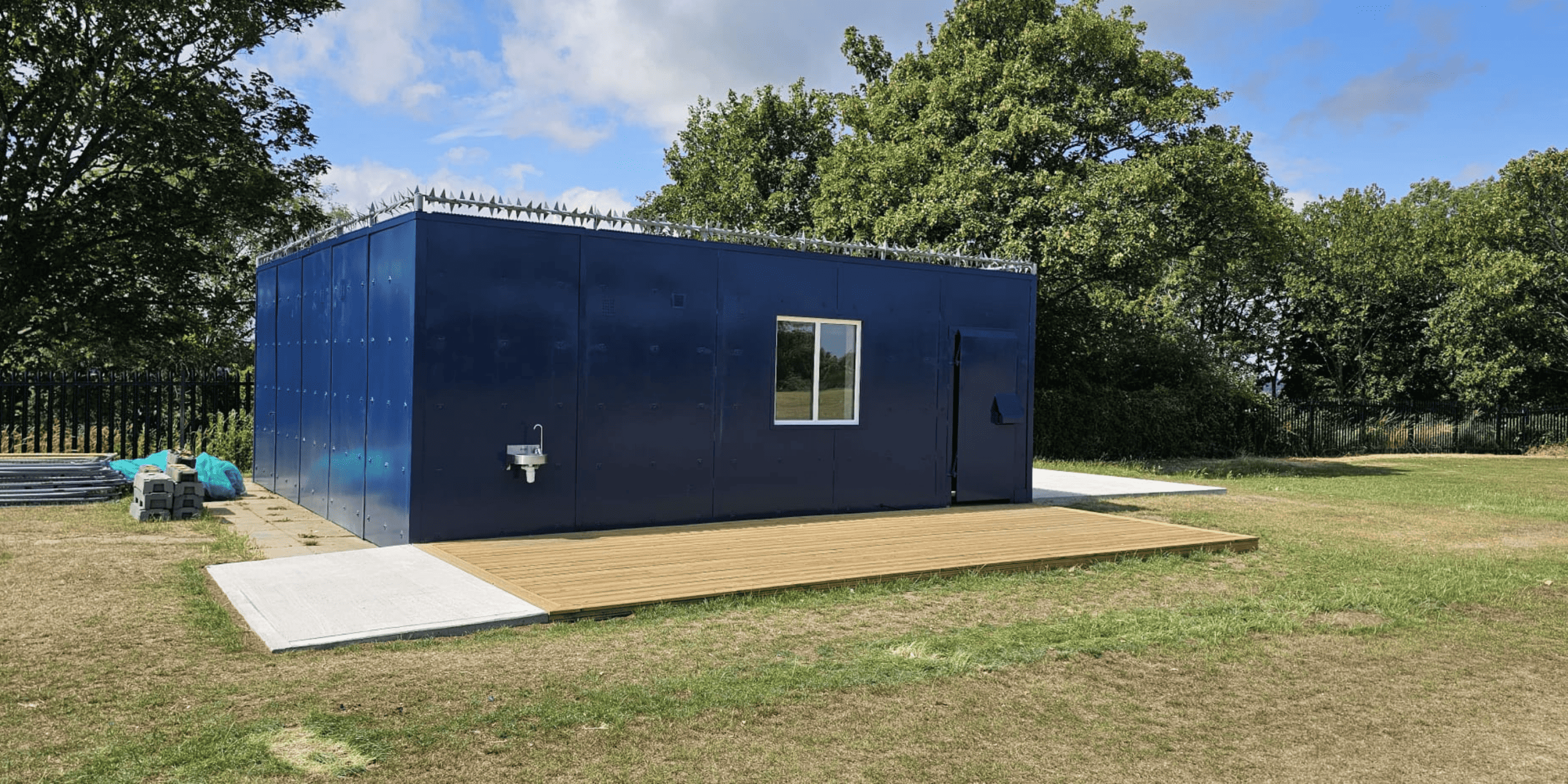 Blue modular building unit on grassy field at Kings School with white-framed windows