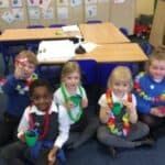 group of pupils wearing paper necklaces and holding cups of water