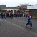 large group of pupils in school playground with some carrying buckets of water and racing