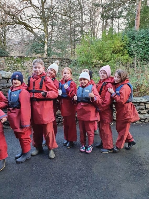 pupils on an external trip wearing waterproofs standing in a row