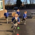 four pupils running excitedly in the school playground