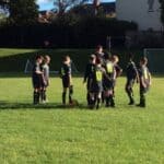 football players standing in a circle being spoken to by the coach