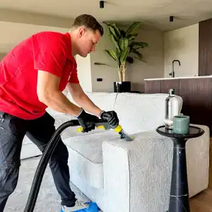 Snelreinigers die een bank in een woonkamer reinigen met professionele apparatuur.