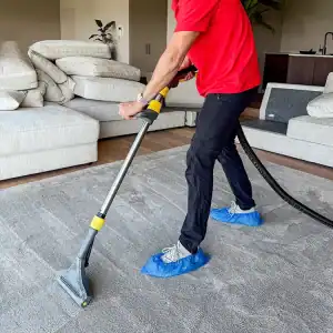 Persoon zuigt tapijt schoon met professionele stofzuiger.