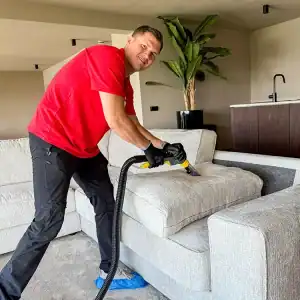Man reinigt bank met professionele stofzuiger in modern interieur.