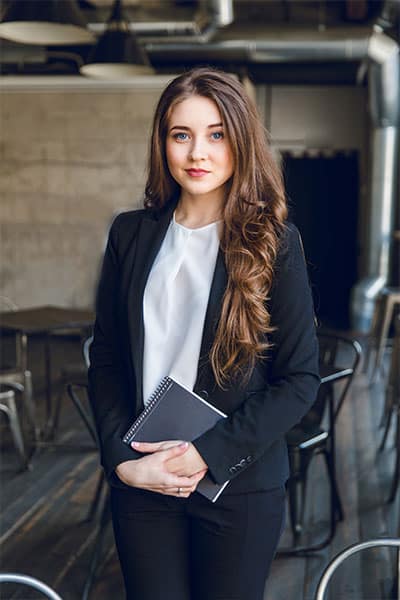 Professional woman holding a notebook in a modern office environment.