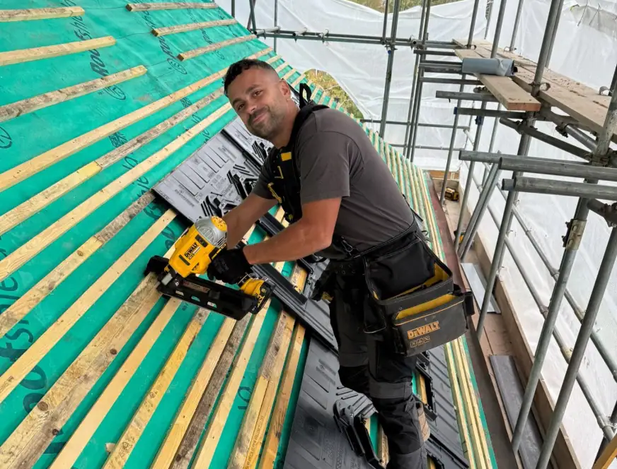 High-quality roofing installation with a professional installer using power tools on a construction site.