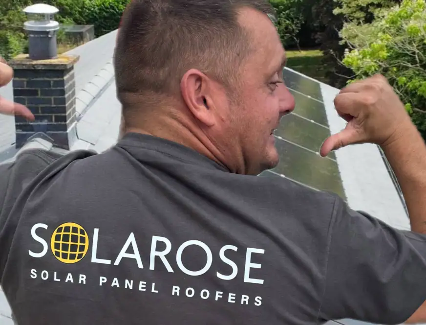 Close-up of a solar panel roofer smiling and working on installing solar panels on a roof, highlighting professional solar roof maintenance and installation services.