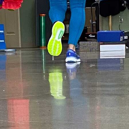 Bright yellow and green running shoes on a person at Rock City Running store, demonstrating athletic footwear for runners and active lifestyle.