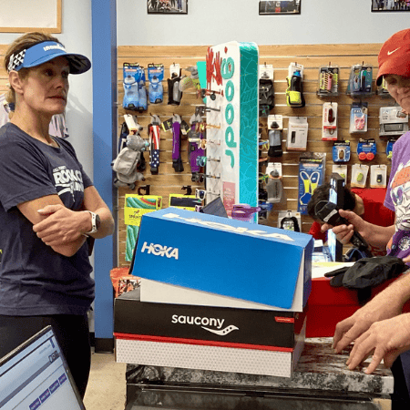 High-quality running shoes and gear display at Rock City Running store with customers shopping and staff assisting, emphasizing athletic footwear and apparel.