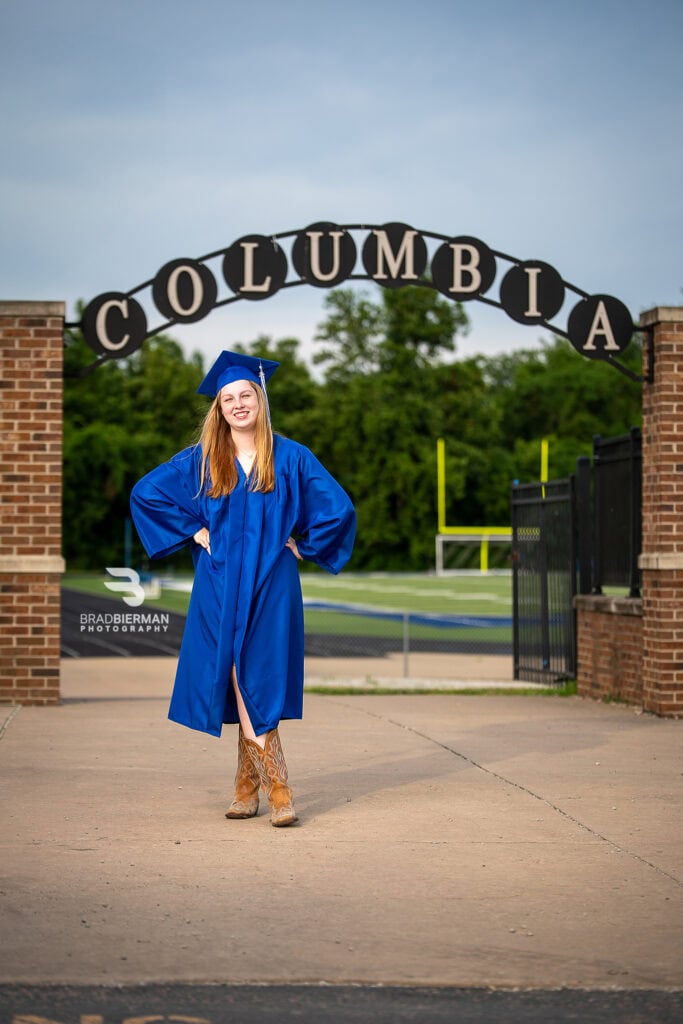 Fun senior portrait of Iz Snyder laughing in her cap and gown on the Columbia High School campus
