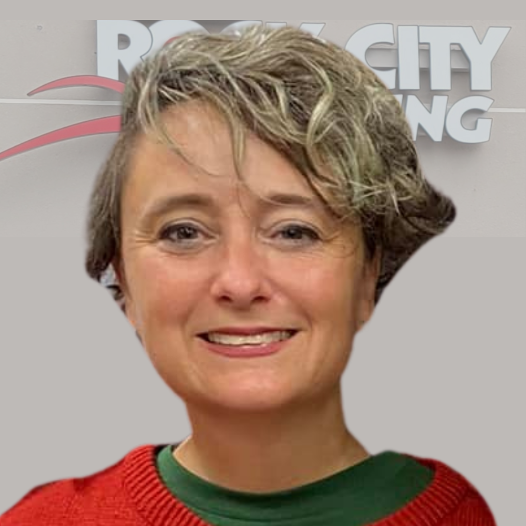 Smiling woman in a red and green sweater, standing in front of Rock City Running signage in Little Rock, Arkansas.