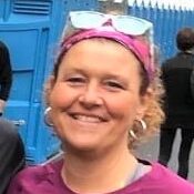 Vibrant female runner smiling at Rock City Running event in a lively outdoor setting.
