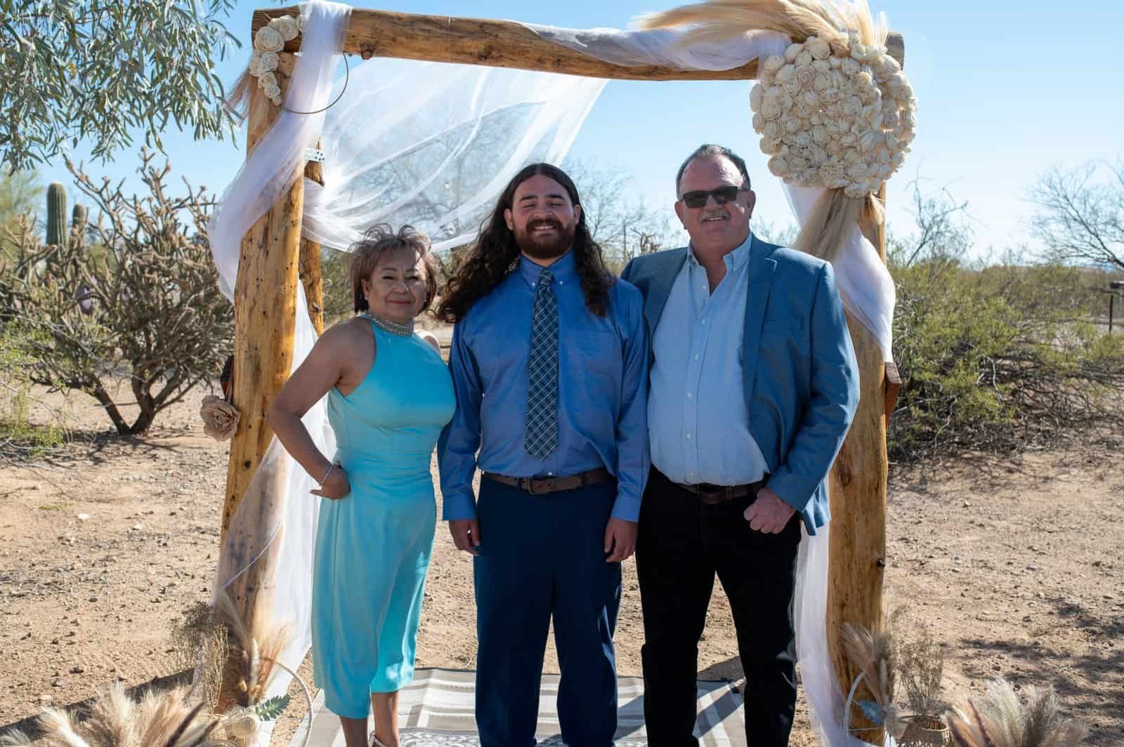 Capturing a special moment during a desert wedding with family and friends under a beautifully decorated arch.