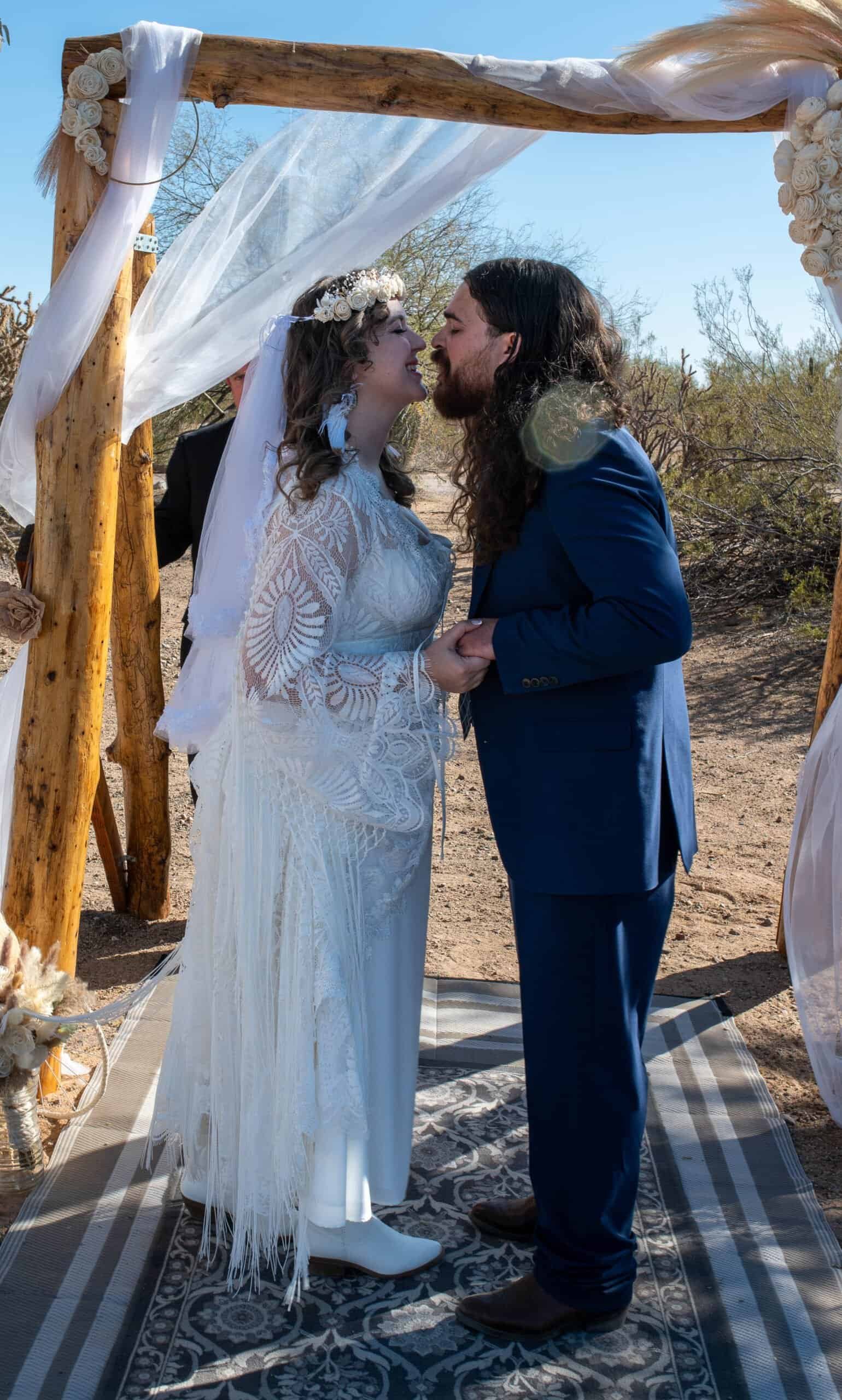 Beautiful outdoor wedding with a rustic wooden arch, bride and groom sharing a special moment.