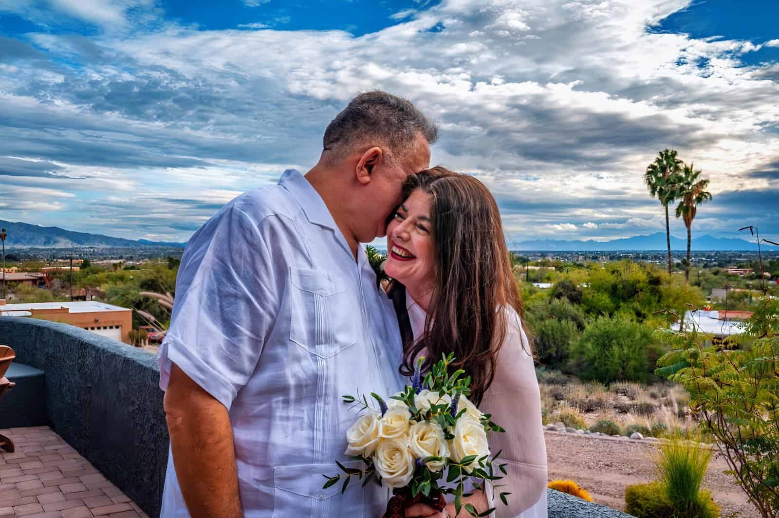 A joyful couple sharing a special moment outdoors with a beautiful sunset and desert scenery in the background.