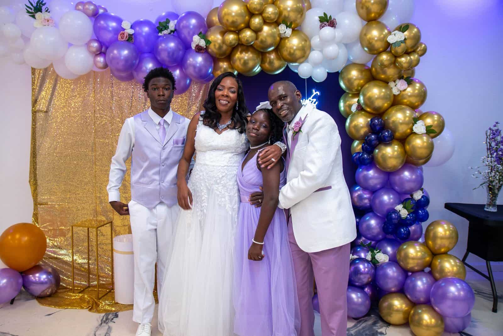 Happy family portrait at a festive event with vibrant balloon decor and smiles.