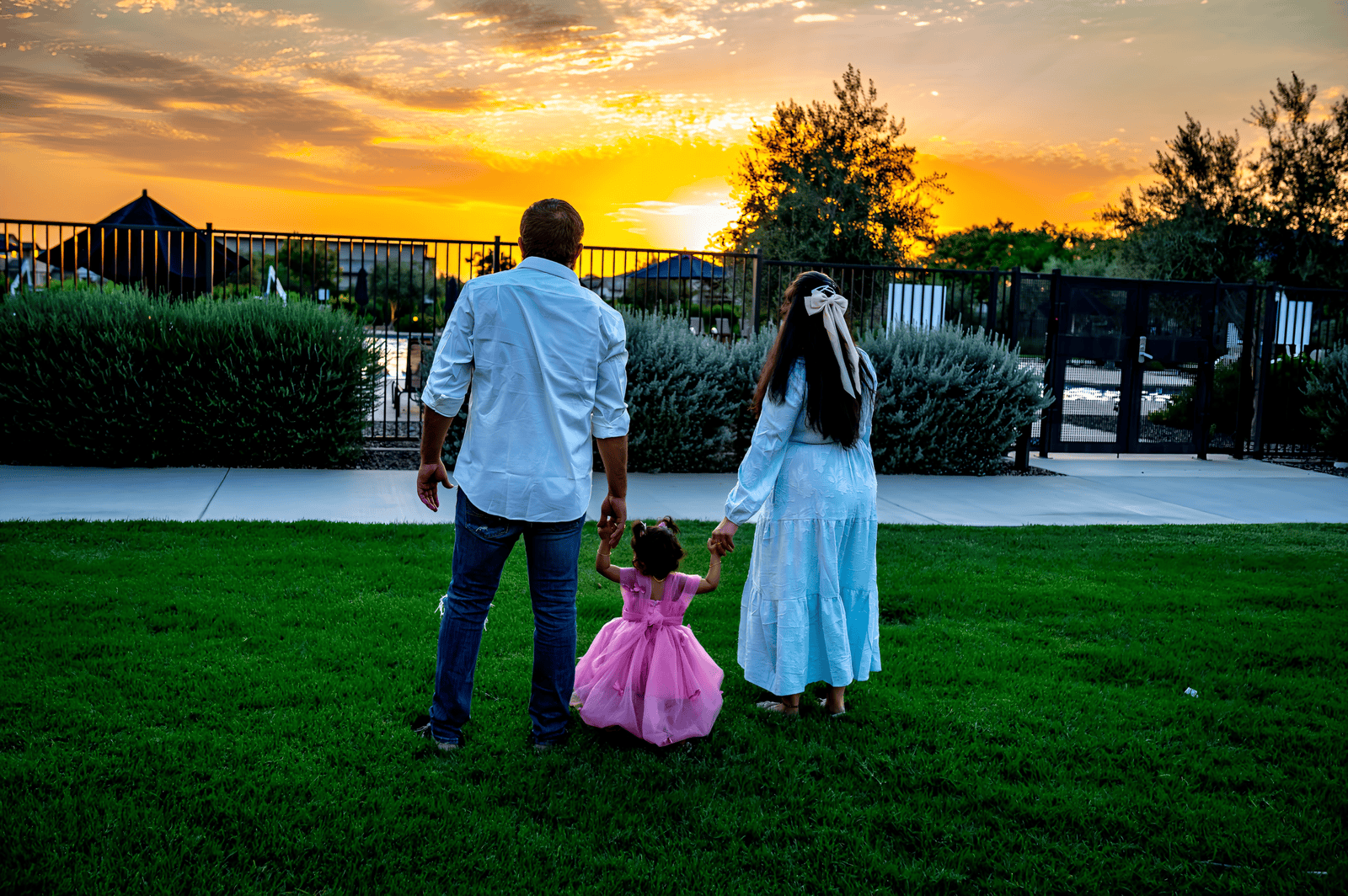 Beautiful family moment during sunset in a park with a child in a pink dress.