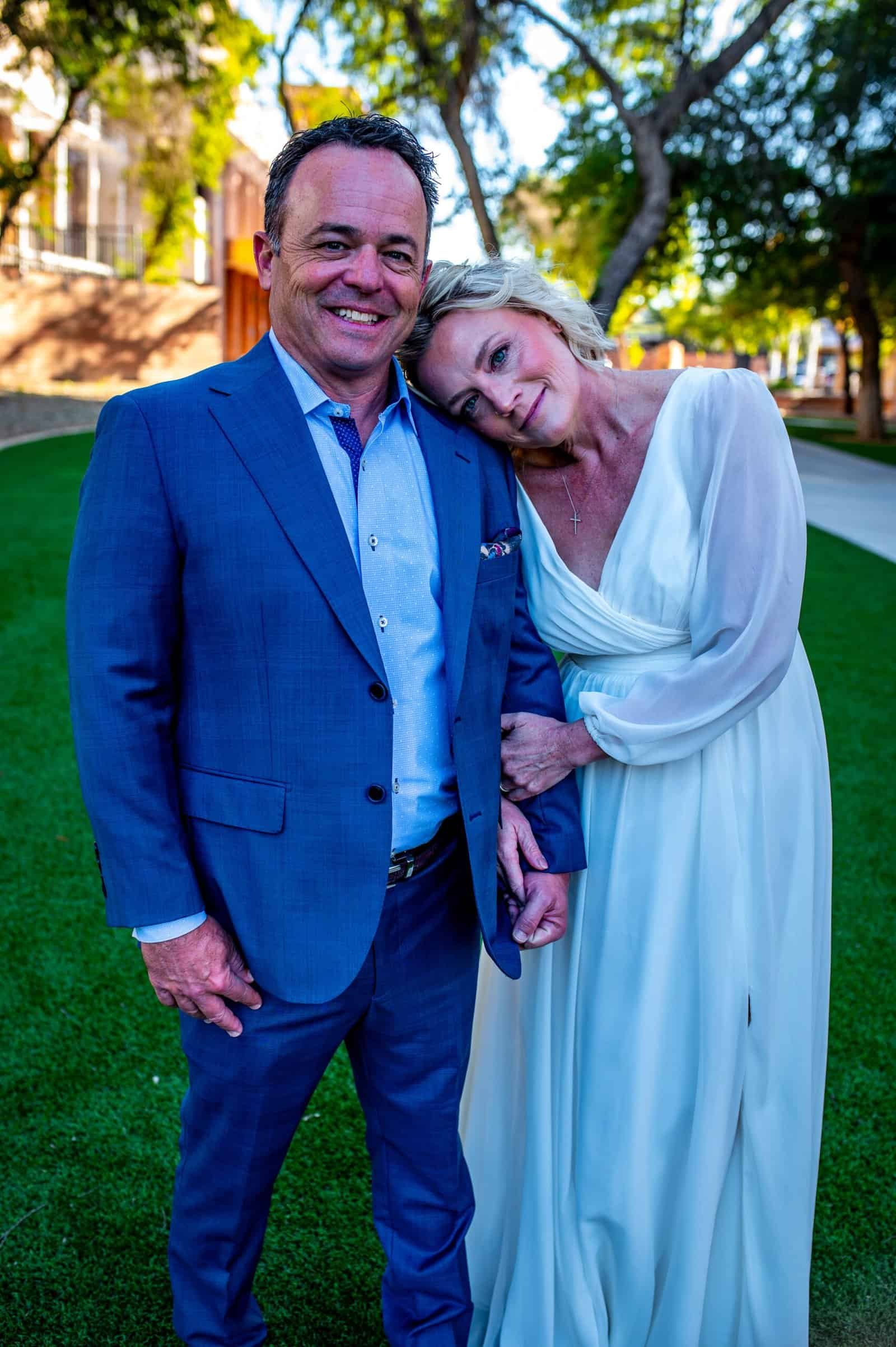 Joyful couple at wedding celebration outdoors in a lush green park setting.