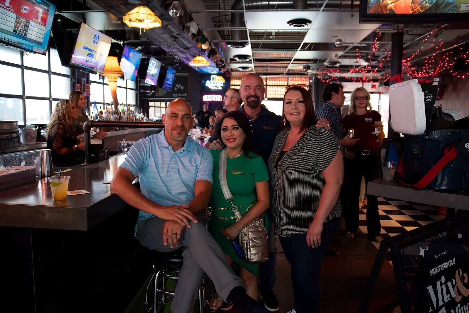 Friends having a great time together at a vibrant bar with colorful lighting and a fun atmosphere.