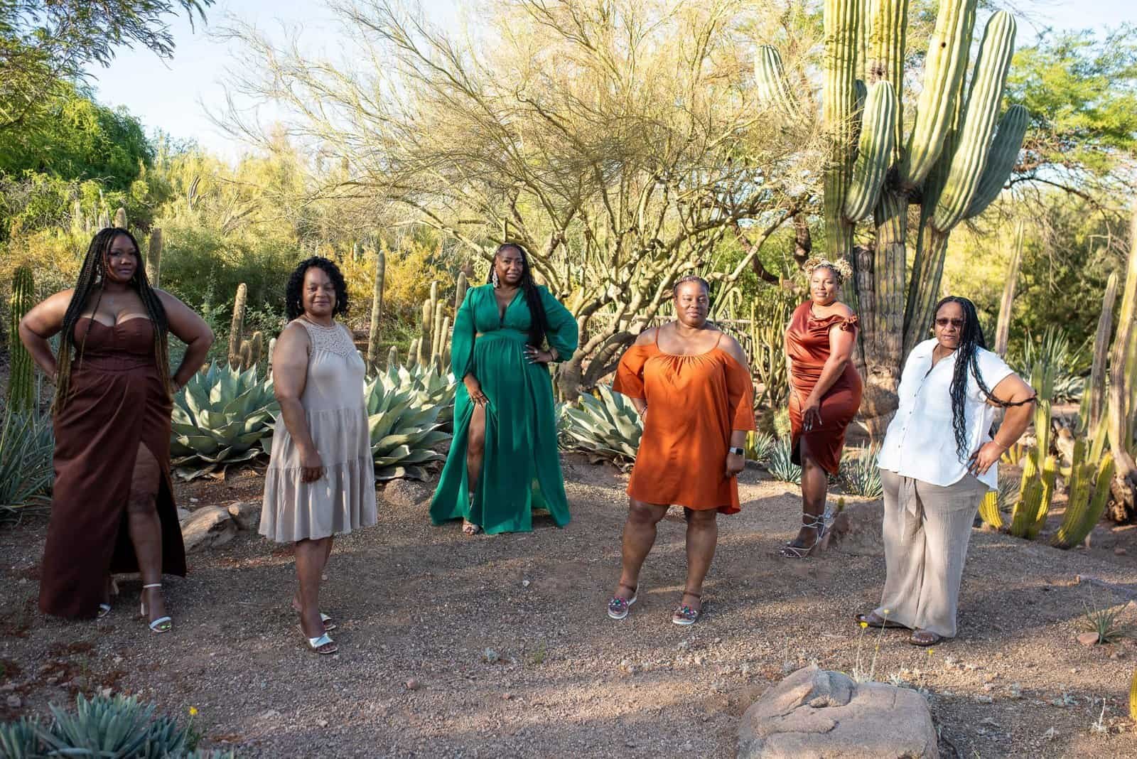 Group of women standing confidently in a desert garden with cacti and trees, celebrating a special occasion.