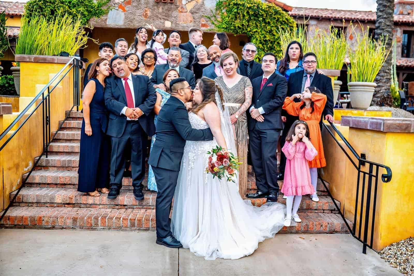 A joyful wedding gathering featuring the bride, groom, family, and friends at an outdoor venue.